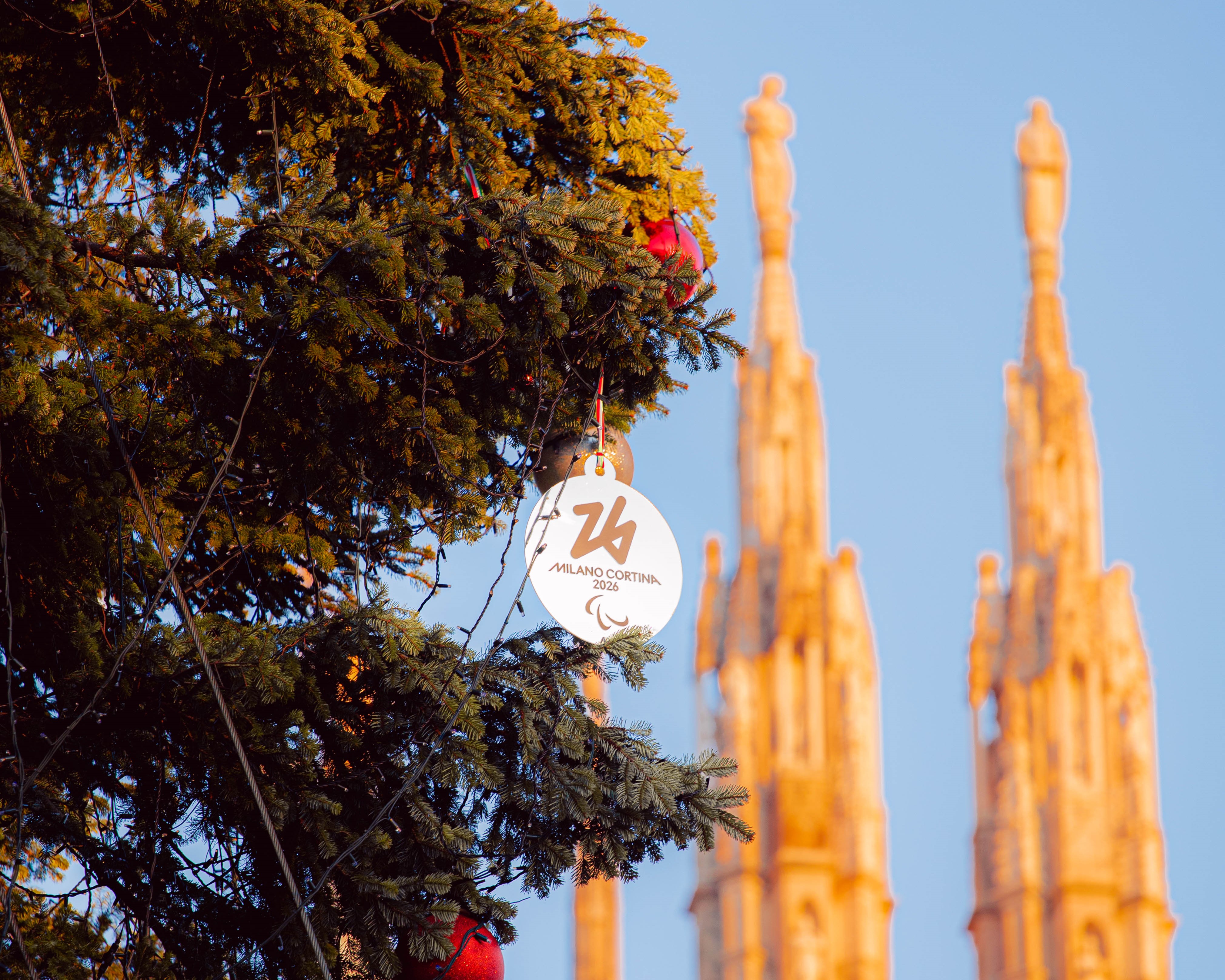 Foto di dettaglio della medaglia di Milano Cortina 2026 appesa ad un ramo dell'albero di natale posizionato in piazza Duomo 